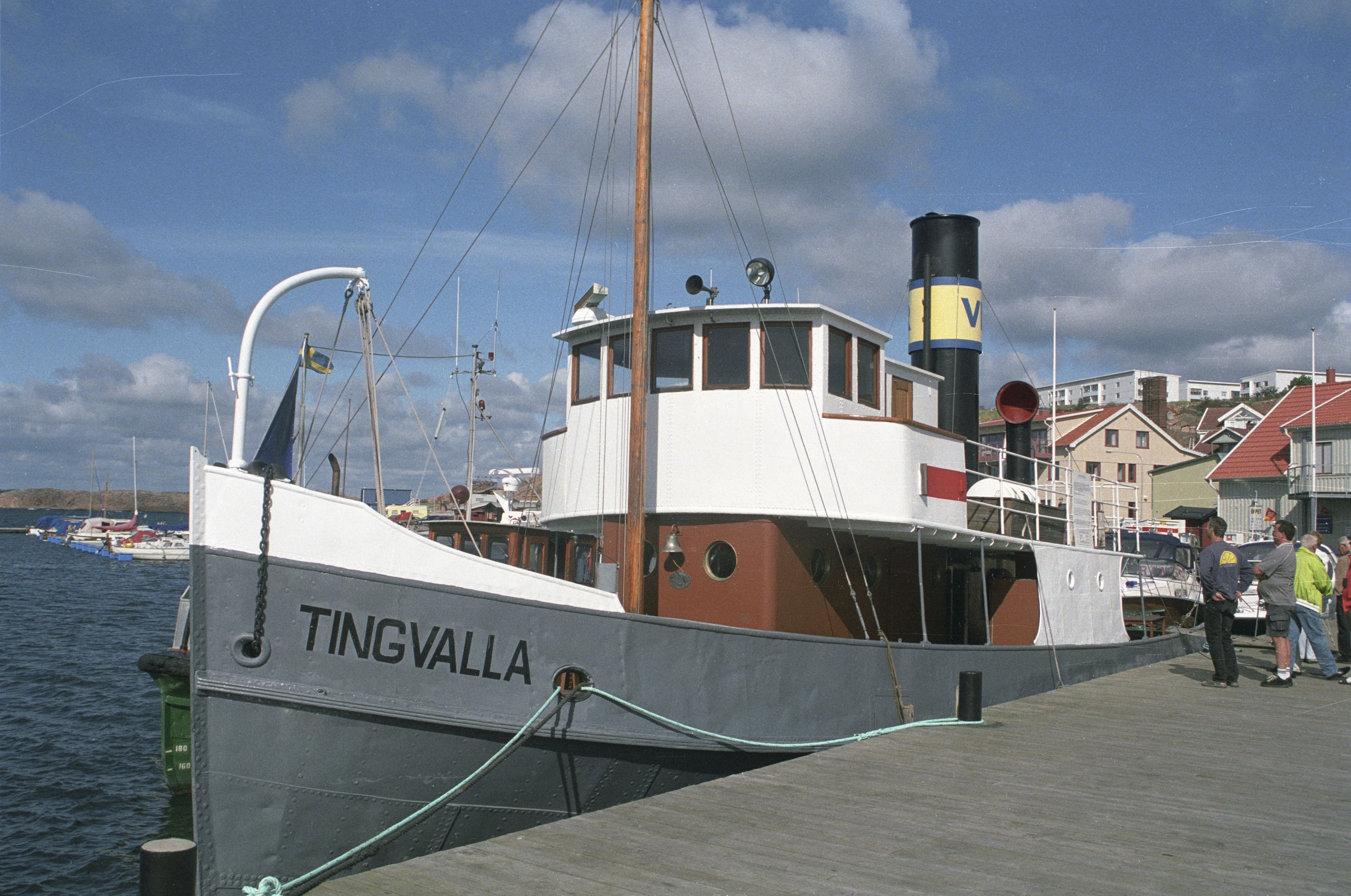 Tingvalla är en bogserbåt med grått skrov och vit överbyggnad. På övre däck finns en kommandobrygga och bakom den en skorsten med ett gult emblem. På fördäcket finns en ljusbrun mast av trä. På bilden ligger fartyget vid kaj i Karlstads hamn. 