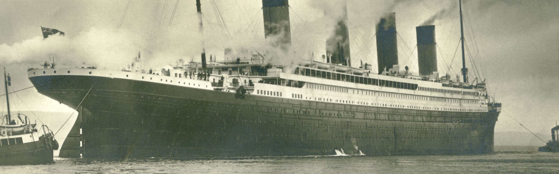 Svartvitt foto av emigrantfartyget RMS Titanic som bogseras. Public Domain